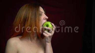 红发女人慢慢地从一个绿色的大苹果上咬下一块
